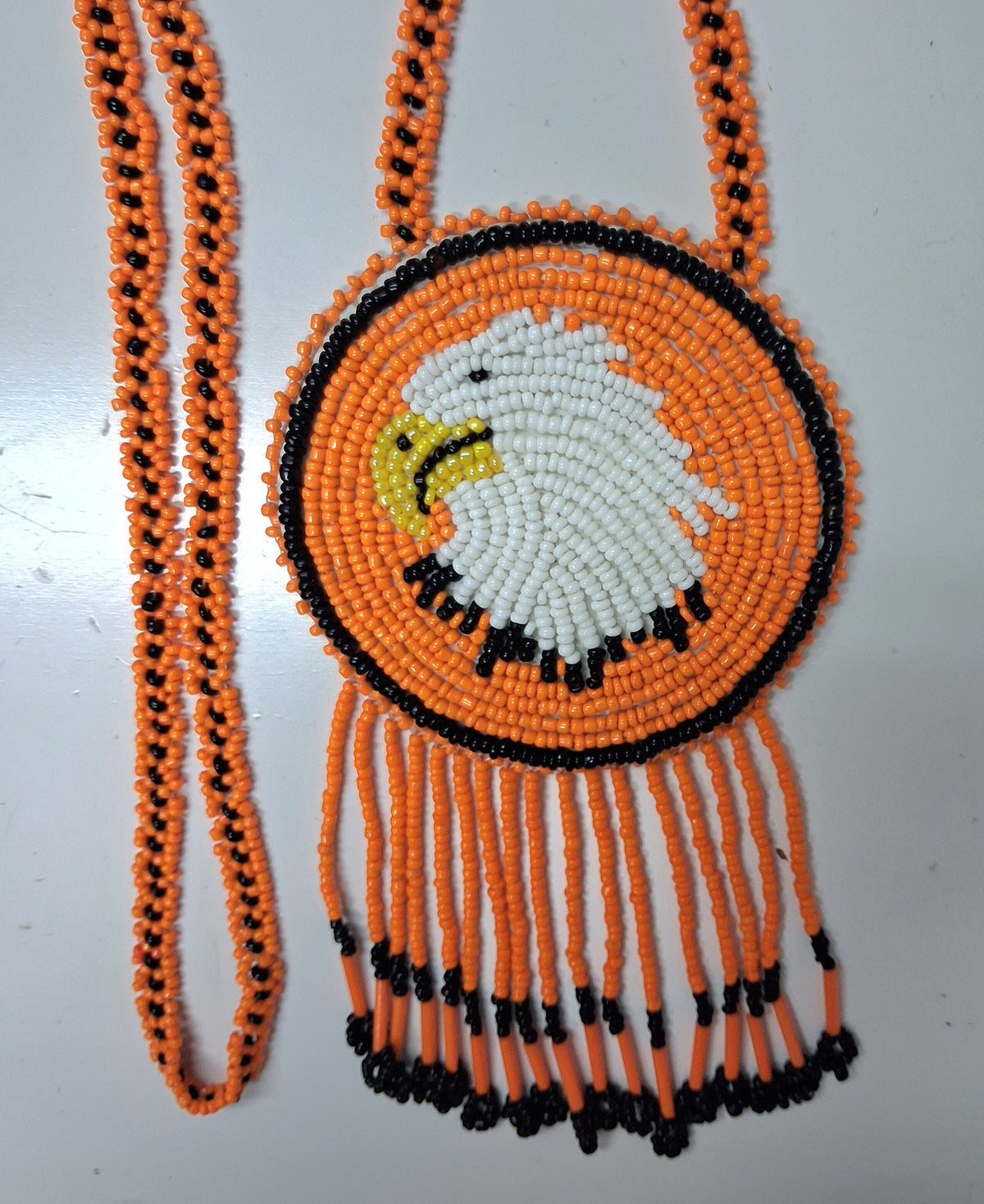 3 1/4" Beaded Eagle Medallion Necklace w/ 29" beaded chain and 2 1/2" fringe. Leather backing. Orange